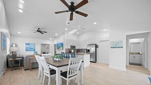 A spacious kitchen with white cabinets, a central island, and a dining area with a table and chairs. - The Jupiter Hideaway (Jupiter)