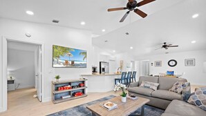 A modern living room with a sofa, coffee table, and a painting of a beach scene. - The Jupiter Hideaway (Jupiter)
