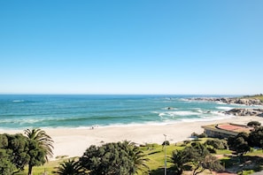 A beach with clear skies, a sandy shore, and a building with a red roof.