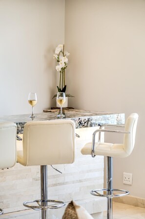 A dining area with a marble countertop, two white chairs, and a vase with white flowers. - Ocean View Camps Bay 3bed Apt Beach Vistas (Cape Town)
