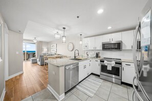 A modern kitchen with stainless steel appliances, a large island, and a view to the living area.