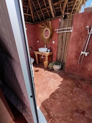 Un baño pequeño con un mueble de tocador de madera, un lavamanos y una zona de ducha.