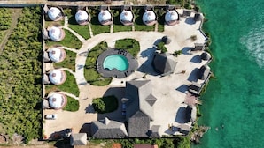 An aerial view of a resort with a central swimming pool, multiple dome-shaped structures, and a beach area. - Paradise city (Kidoti)