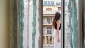 A person standing by a window with a view of a building and balconies. - Mia Homes - Heart of Athens, Mia Homes (Athens)