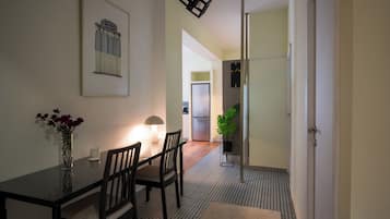 Un coin repas comprenant une table, des chaises, un vase de fleurs, une lampe et un tableau encadré accroché au mur.