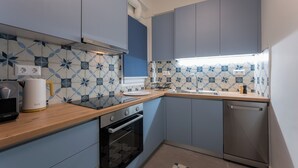 Une cuisine moderne avec des armoires bleues, un plan de travail en bois, un four encastré et un évier.