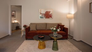 Un salon moderne avec un canapé marron, deux tables rondes, un vase de fleurs et un tableau encadré au mur.