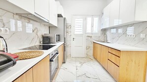 A modern kitchen with white cabinets, a marble backsplash, and a wooden countertop.