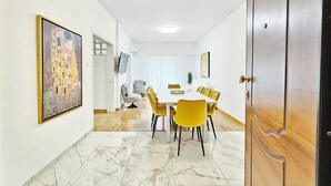 A dining area with a white table, yellow chairs, and a painting on the wall.