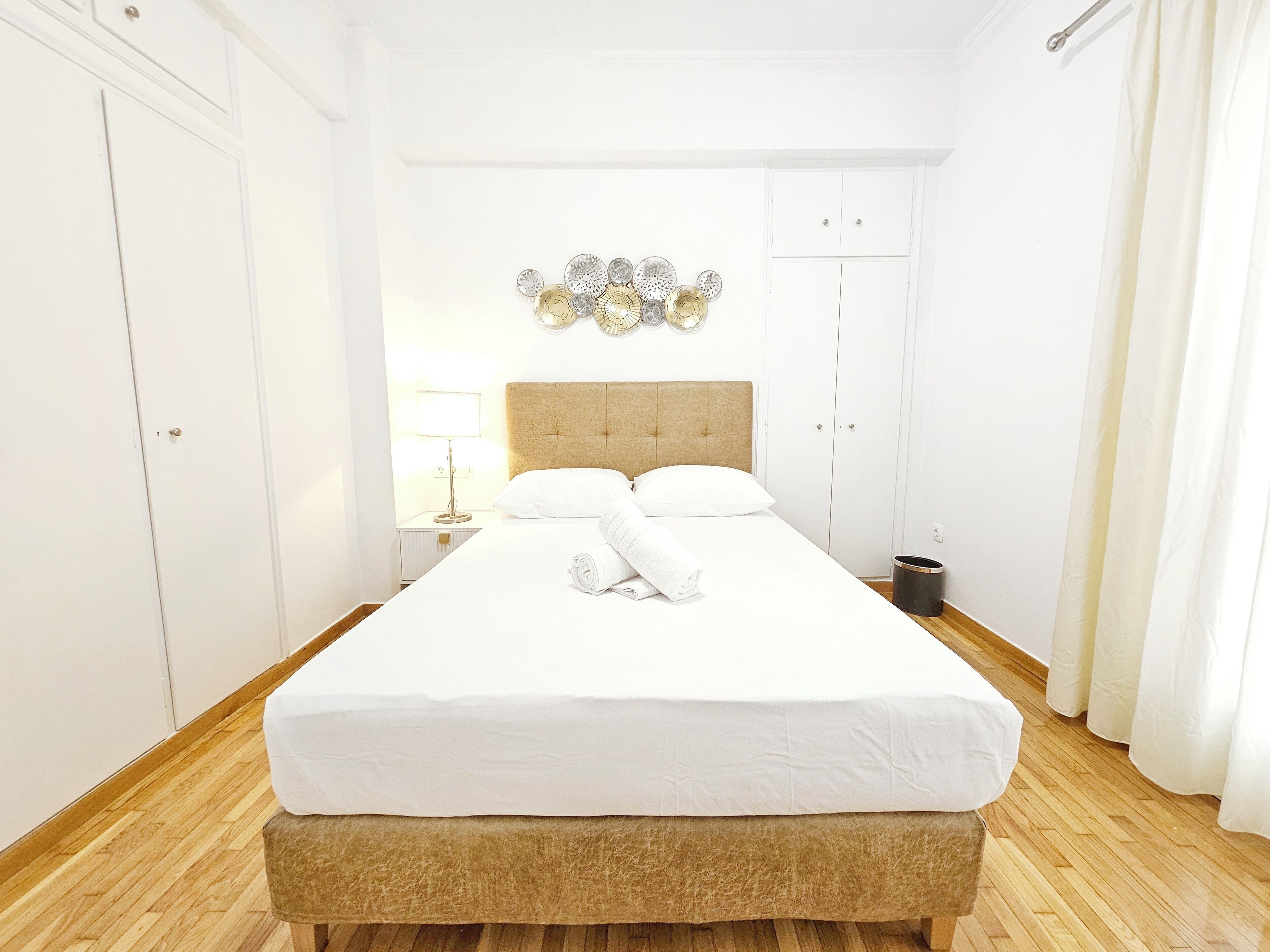 A neatly made bed with white linens, a wooden headboard, and a small bedside table with a lamp.