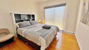 A bedroom with a bed, a chair, a nightstand, a ceiling fan, and a window with blinds. - Seascape - Kalbarri, WA (Kalbarri)