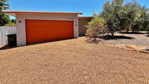A modern single-story house with a red garage door, a small tree in the front yard, and a clear blue sky. - Seascape - Kalbarri, WA (Kalbarri)