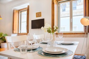 A dining table set with plates, glasses, and a vase of flowers. - Central Apartment at Chiado (Lisbon)