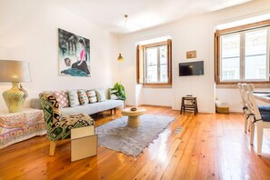 A living room with a sofa, a coffee table, a TV, and a window. - Central Apartment at Chiado (Lisbon)