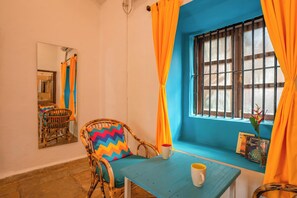 Um quarto com janela, mesa, cadeira e espelho.