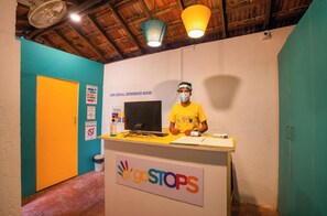 A reception desk with a 'goSTOPS' sign, a computer, and a person wearing a yellow shirt. - goSTOPS Lite Goa, Calangute (Calangute)