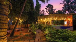 A well-lit outdoor area with a pool, surrounded by lush greenery and palm trees. - goSTOPS Lite Goa, Calangute (Calangute)