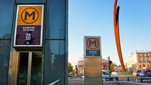 Een modern gebouw met een glazen gevel en een bord dat een parkeerplaats voor 'Barrière de Paris' aangeeft.