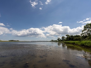 Un río tranquilo con cielo despejado y algunas nubes dispersas.