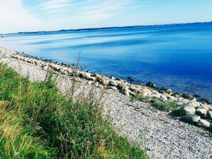 Una costa rocosa con aguas azules cristalinas y tierra a lo lejos.