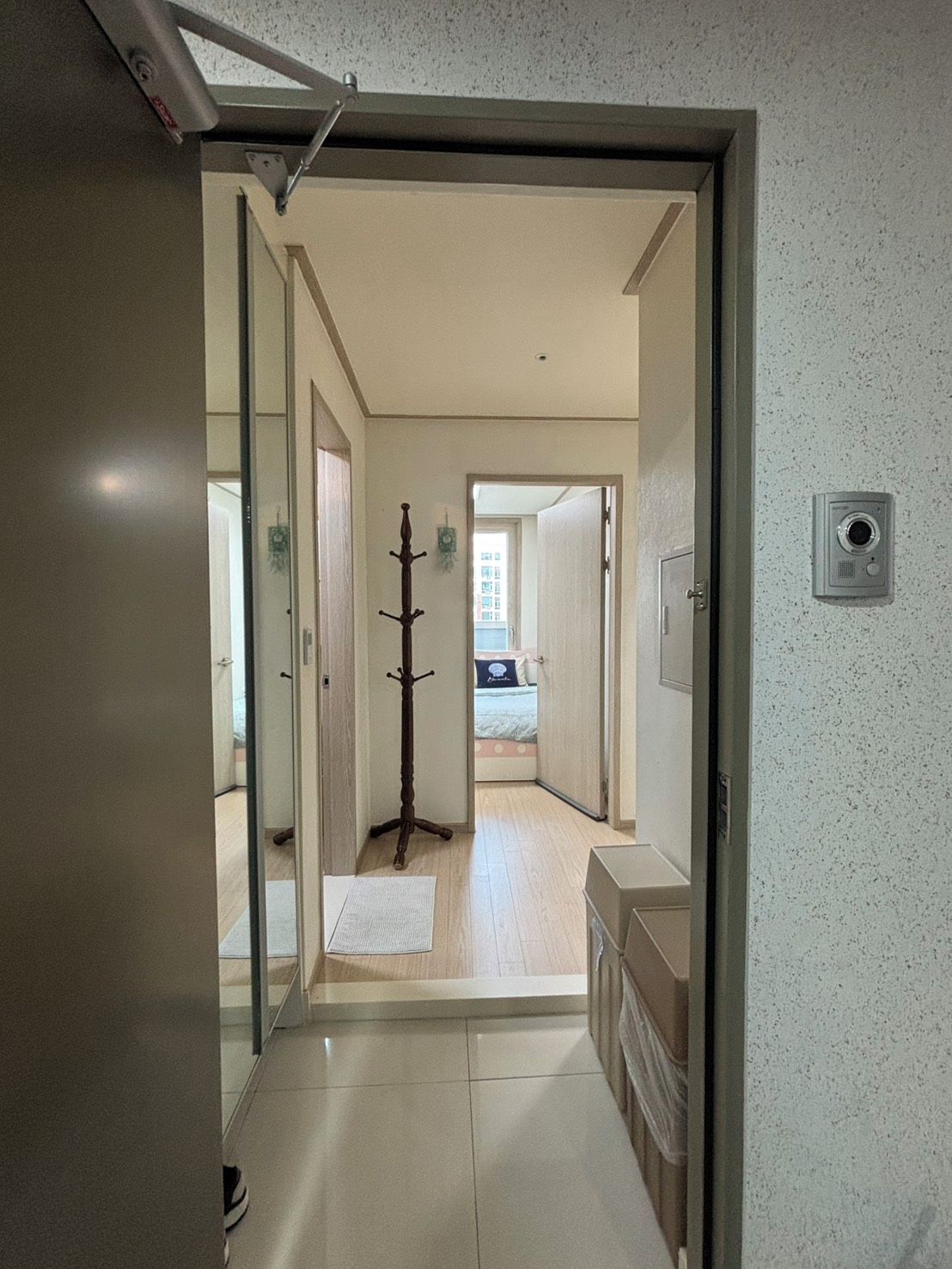 Un pasillo con un perchero, una puerta que da a otra habitación e interruptor de luz en la pared.