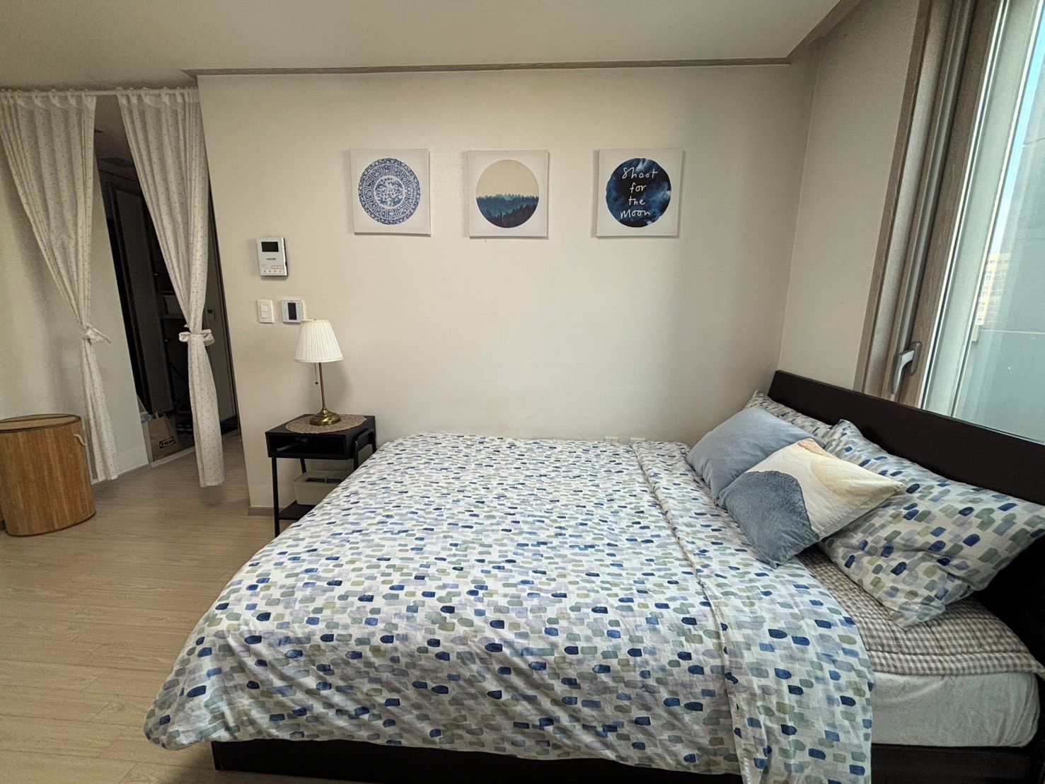 Une chambre à coucher comprenant un lit, une table de chevet, une lampe et trois œuvres d’art murales.