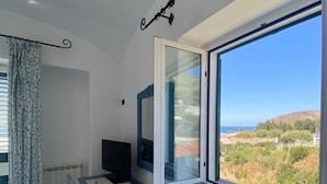 Una stanza con un tavolo e sedie, una TV, una finestra vista paesaggio e una tenda.