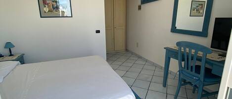 Ein Schlafzimmer mit einem Bett, einem Schreibtisch, einem Stuhl und einer Tür.