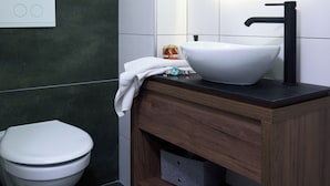 A modern bathroom with a white toilet, a wooden vanity with a white sink, and a mirror above the sink. - Brent Collection (Novi Sad)