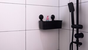 A shower area with a black hose and a shelf with toiletries. - Brent Collection (Novi Sad)