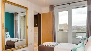 Habitación de hotel con un espejo grande, dos camas, un armario y puerta corrediza de vidrio a un balcón.