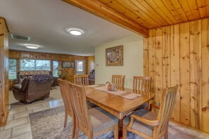 A wooden interior with a dining table, chairs, a sofa, and a fireplace.
