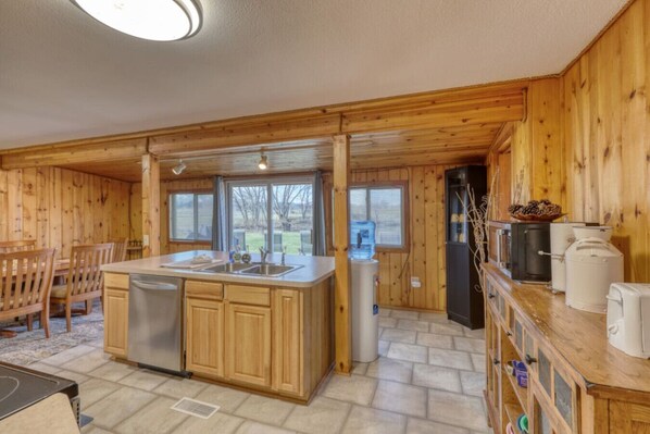 A wooden cabin kitchen with a central island, a refrigerator, and a water dispenser.