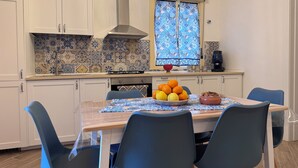 A modern kitchen with white cabinets, a gas stove, and a window with patterned curtains. - Dimora del Tufo Antico - House in the heart of Avola (Avola)