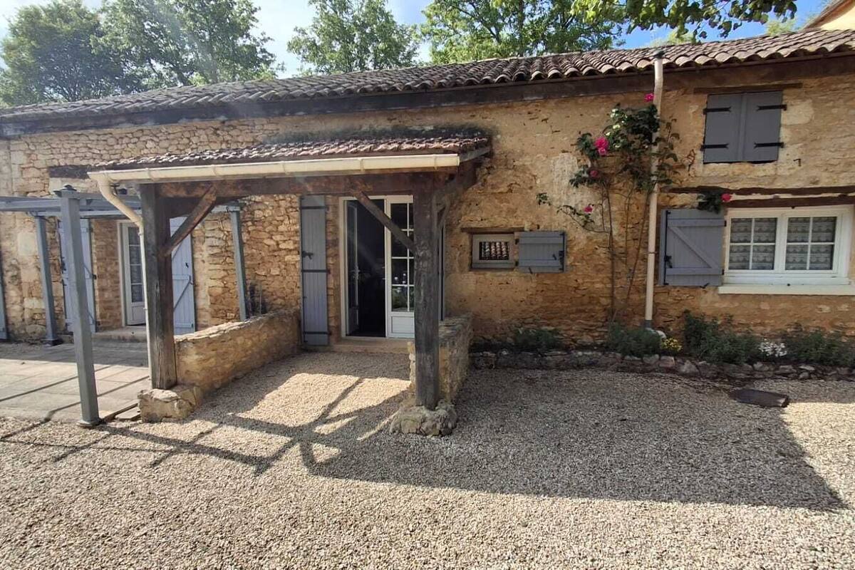 A rustic stone building with a covered entrance and a gravel driveway.