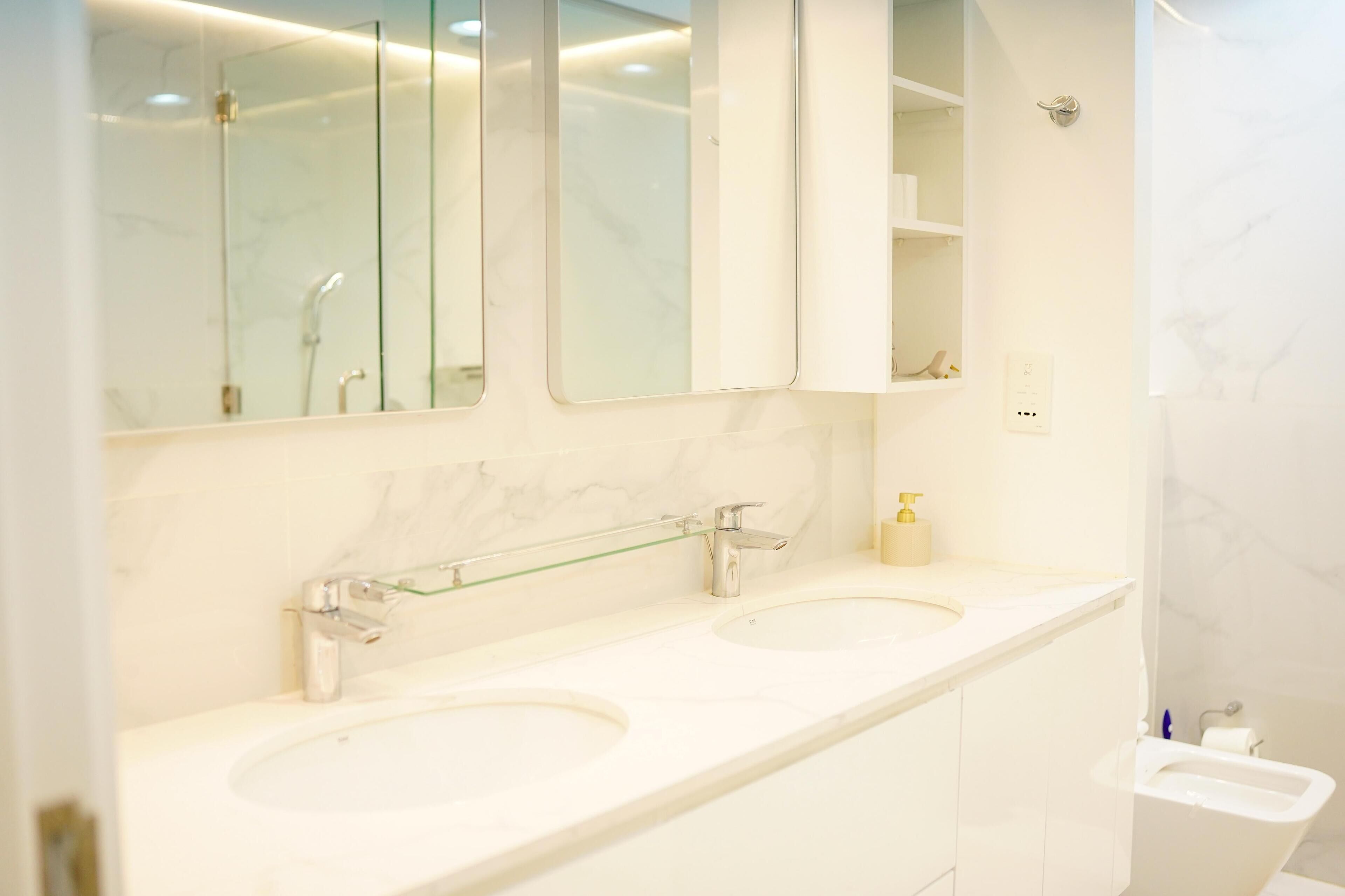 A modern bathroom with two sinks, a glass shelf, and a mirror above the sink.