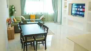 A modern living room with a sofa, a dining table, and a TV mounted on the wall. - Zapbed House - LW 2007 (Dubai)