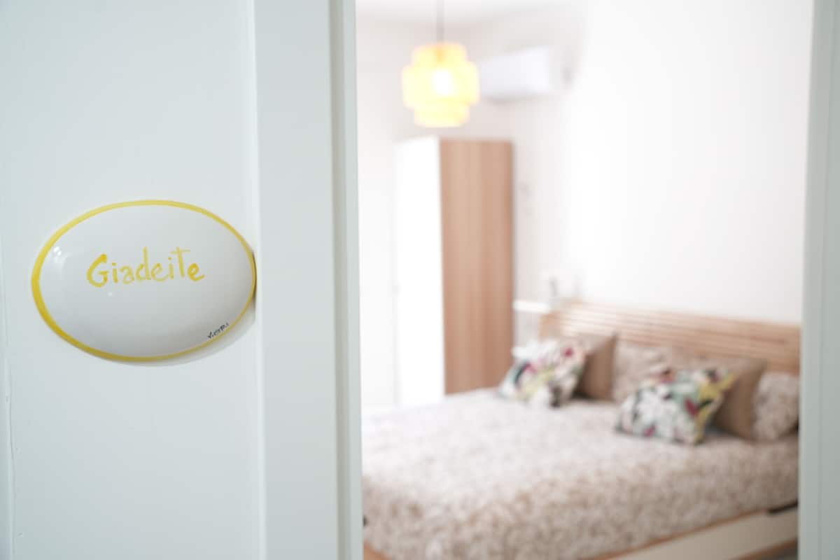 A room with a bed, a hanging light fixture, and a sign on the wall.