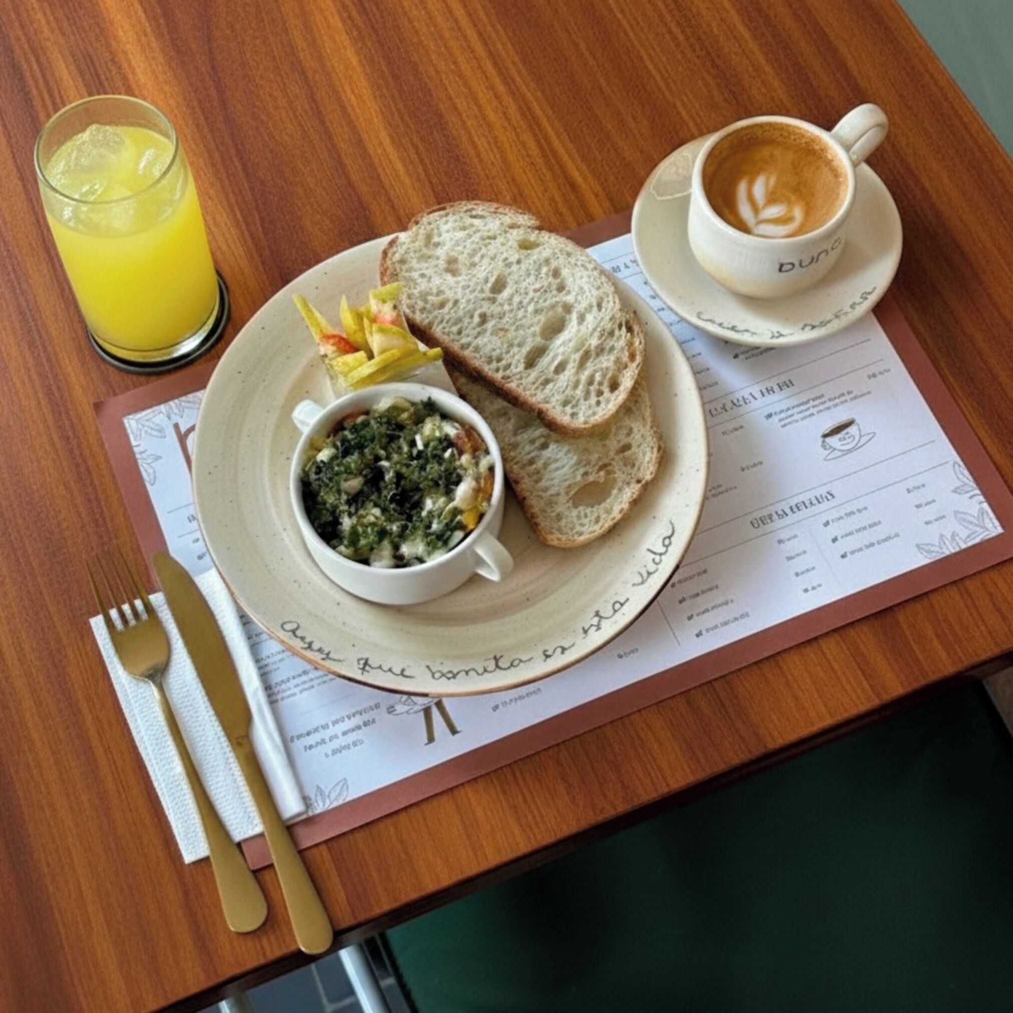 Eine Mahlzeit mit Brot, eine Tasse Kaffee und ein Glas Saft auf einem Holztisch mit einer Speisekarte.