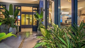 A modern hotel entrance with a glass door, potted plants, and a well-lit interior visible through the door. - Veca Flats Centenario  (Cali)