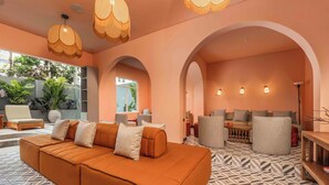 A modern interior with a large orange sofa, multiple seating areas, and a patterned floor. - Veca Flats Centenario  (Cali)