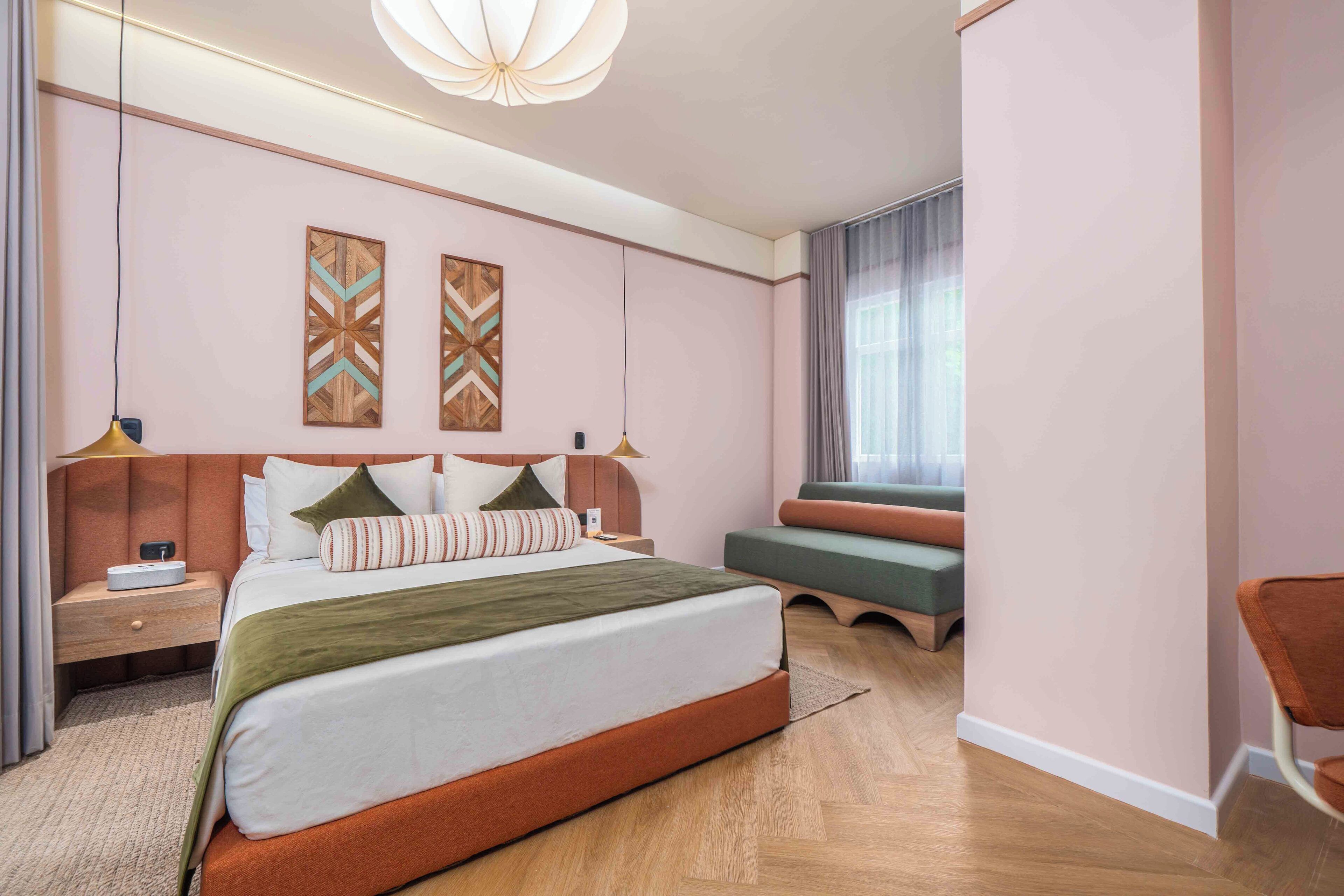 Une chambre d’hôtel moderne dotée d’un grand lit, d’un coin salon et d’œuvres d’art accrochées aux murs.
