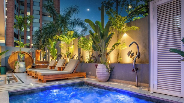 A rooftop pool area with lounge chairs, a hot tub, and tropical plants. - Veca Flats Centenario  (Cali)
