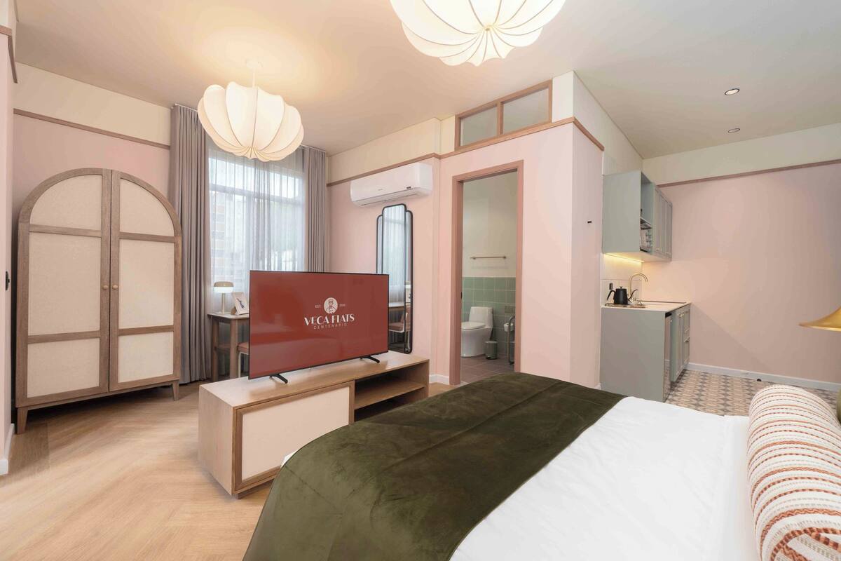 A hotel room with a bed, a TV, a desk, and a wardrobe.