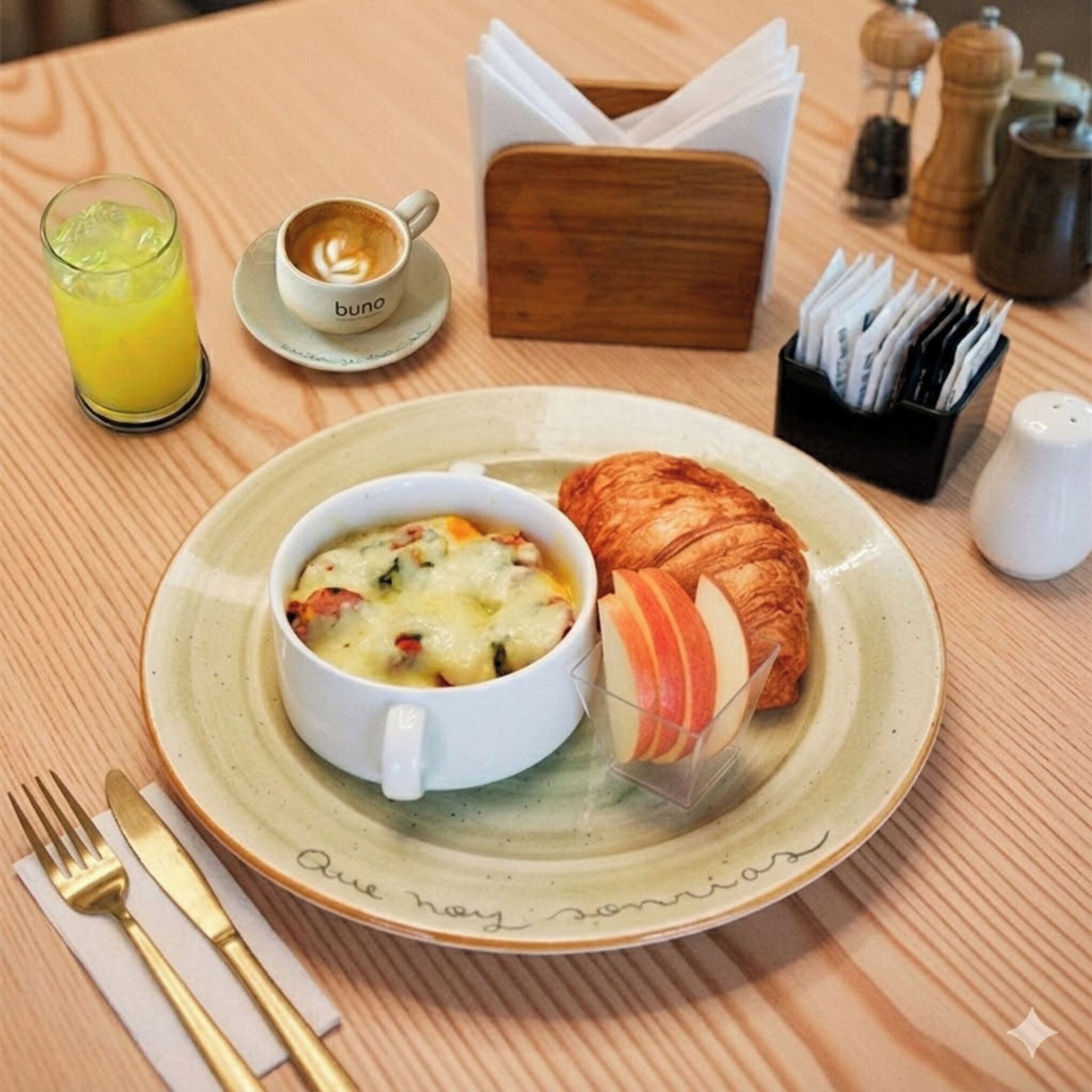 A breakfast setting with a croissant, a bowl of soup, a glass of orange juice, and a cup of coffee on a wooden table.