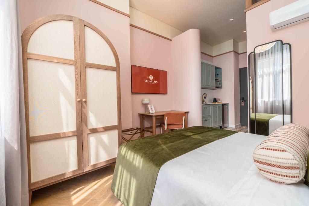 A hotel room with a bed, a desk, a chair, a wardrobe, and a mirror.