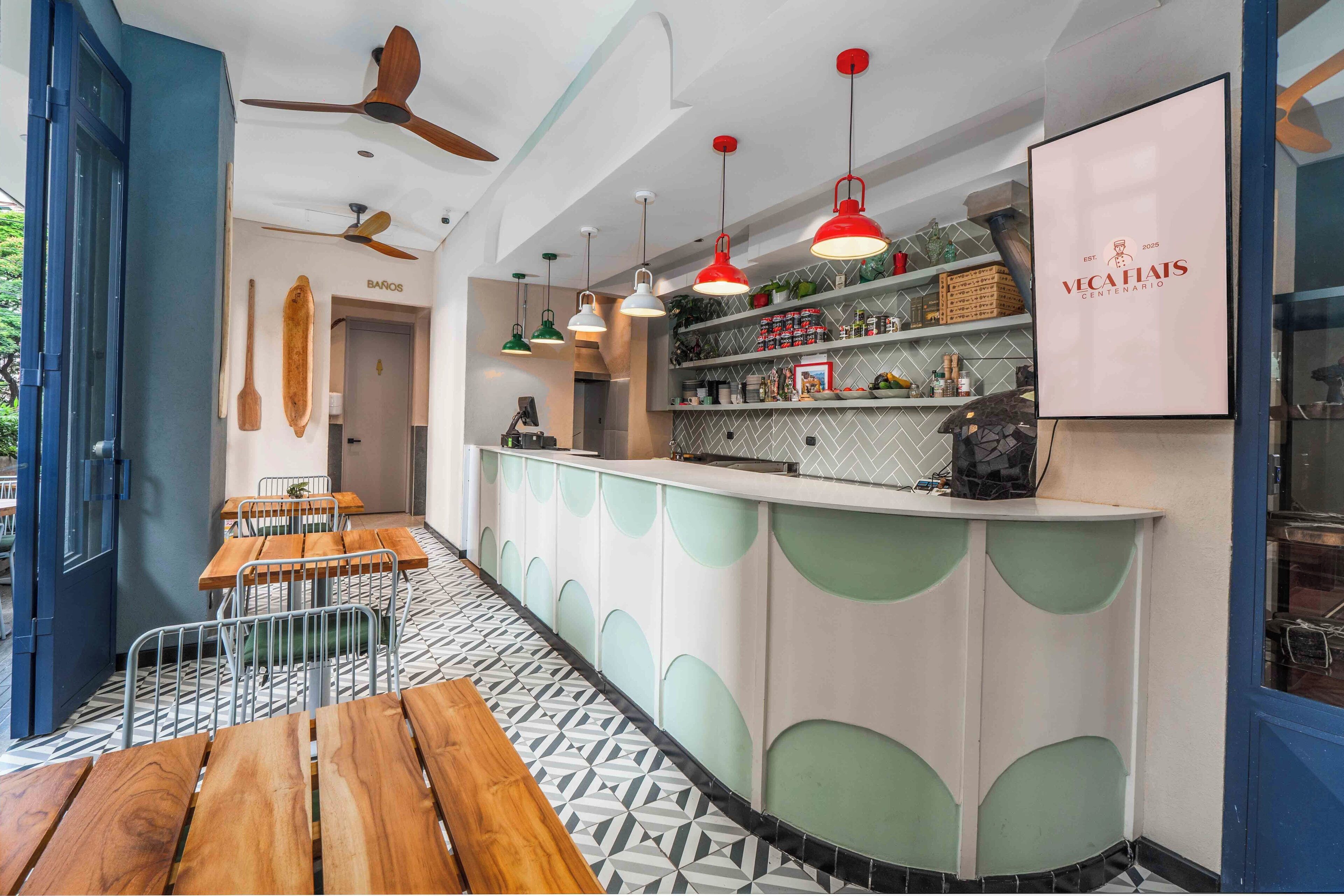 A modern bar area with wooden tables and a counter with shelves of bottles and glasses.