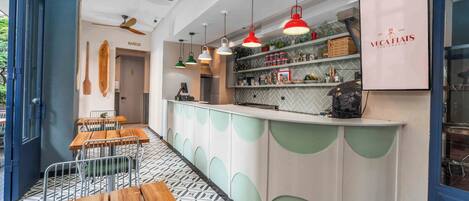 A modern bar area with wooden tables and a counter with shelves of bottles and glasses.