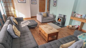 Un salon chaleureux avec un canapé d’angle, une table basse en bois et une cheminée.