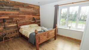 Une chambre à coucher avec un lit en bois, une table en verre et une fenêtre donnant sur l’extérieur.